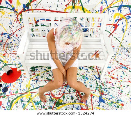 Beautiful woman with white hair, white dress sitting in paint mess, looking down.