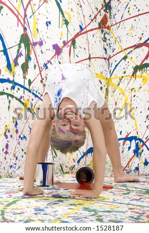 Ten year old girl doing back bend towards camera on paint splashed background.  Full body.