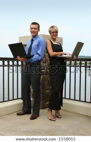 Business man and woman outside with laptops.