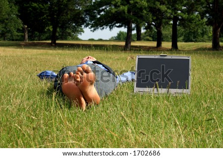 Barefoot man lying in grass takes a break from work