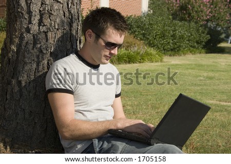 Attractive young college student working outside on laptop.