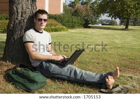 Attractive young college student on campus with laptop.