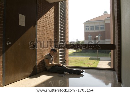 College student sitting in window working on laptop.