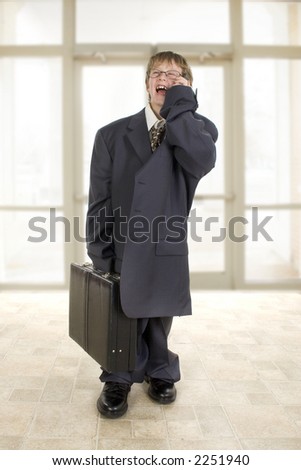 Adorable eight year old boy in father\'s business suit laughing into cellphone.