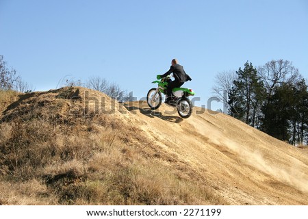 Thrity something business man in suit riding dirt bike on dirt riding track.