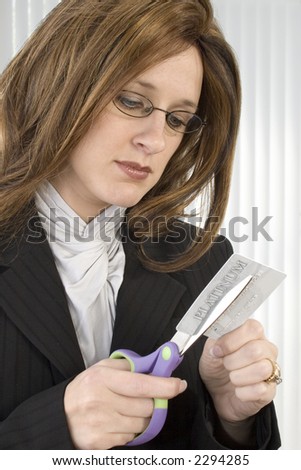 Thirty something business woman cutting up credit card.