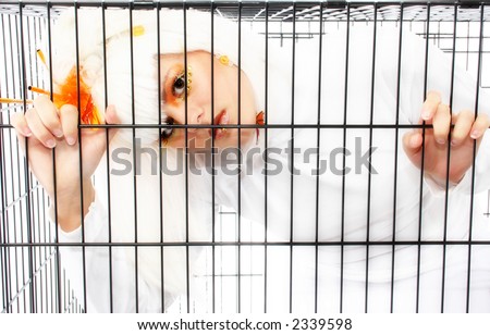 Beautiful young woman with white hair and artistic make-up in dog cage.