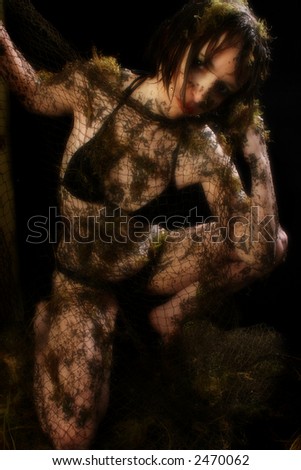 Woman covered in mud, moss and fishnet over black.
