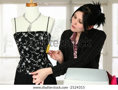 Beautiful retail sales person adjusting mannequin.