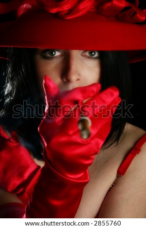 Beautiful thirty something woman with thin cigar.  Red hat, red gloves, over black.
