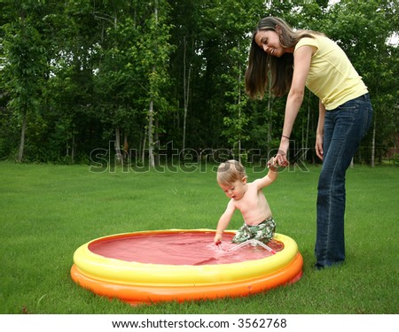 Mom and son playing outdoors in kiddie pool.