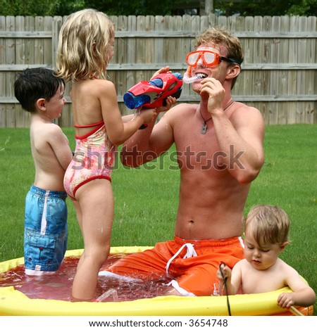 Boys and girl with dad in the kiddie pool.