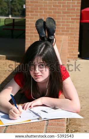 Beautiful 14 year old girl doing homework outside at school.