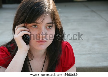Beautiful 14 year old girl on cellphone outside at school.