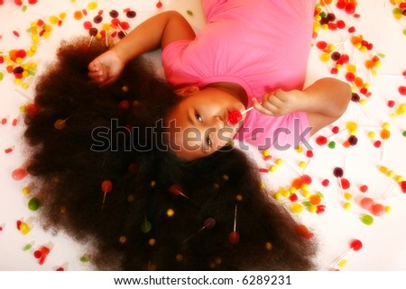 Beautiful 10 year old African American laying on floor surrounded by candies.
