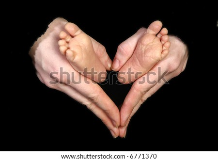 Baby feet held by mother\'s hands making heart shape.