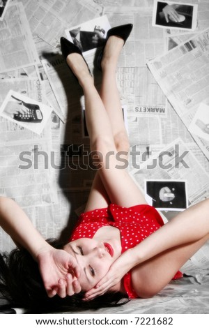 Beautiful young woman laying with feet up on newspaper background.