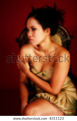 Beautiful twenty something Asian Indonesian mixed womn in gold formal dress on crimson red background.