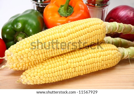 Close up of three ears of corn on cutting board.