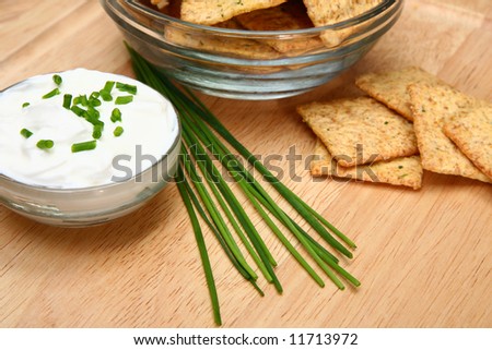 Focus on chives laying between crackers and sour cream.