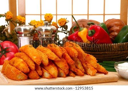 Potato wedges on kitchen or restaurant cutting board.