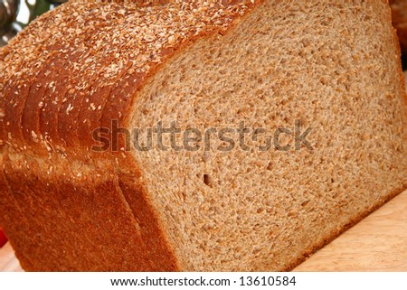 Whole wheat bread sliced on cutting board in kitchen or deli.