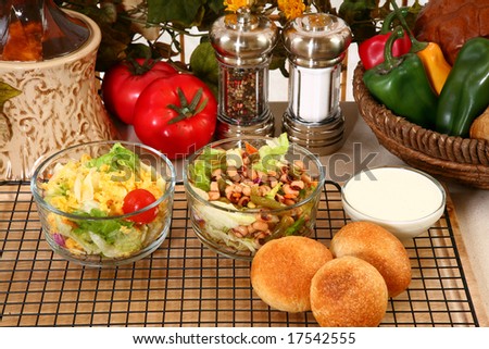 Glass bowl of black eye pea salad, garden salad and rolls in kitchen or restaurant.