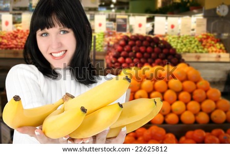 Focus on bananas.  Woman with bananas in supermarket.