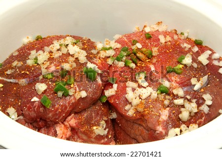 Uncooked roast beef in crock pot covered in onion, jalapeno, pepper, garlic.