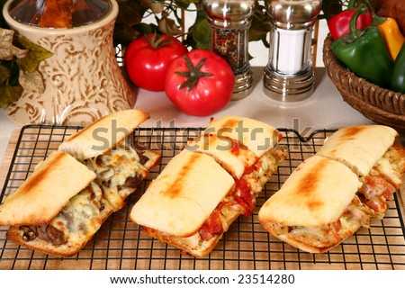 Various toasted submarine sandwiches with chicken, beef, ham, sausage, melted cheese, vegetables, and marinara sauce.