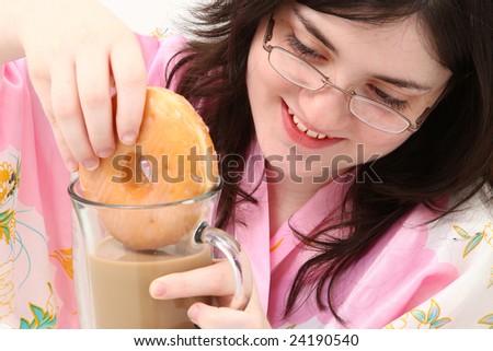 Adorable fifteen year old girl dunking her doughnut into her coffee.