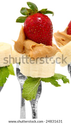 Banana slices, peanut butter and whole strawberries on forks with mint leaves.