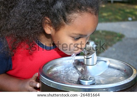 Adorable five year old African American Girl drinking from water fountain