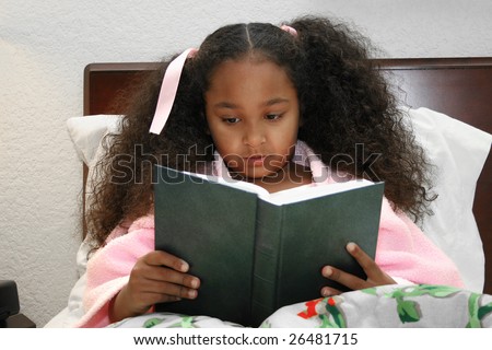 Adorable five year old African American Girl reading in bed.