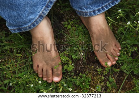 Close up caucasian child's dirty feet and toes in grass.
