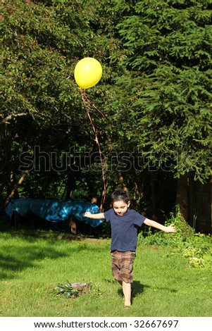 Adorable six year old boy playing with yellow balloon.