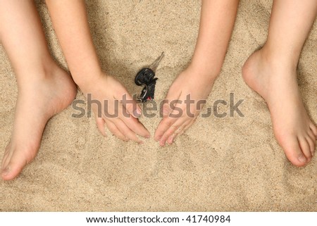 stock photo Young child's hands and feet in sand playing with car keys
