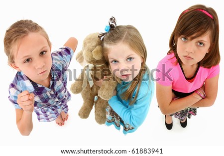 Adorable group of angry 7 year old girls over white background looking up towards camera.  Top view over white background.