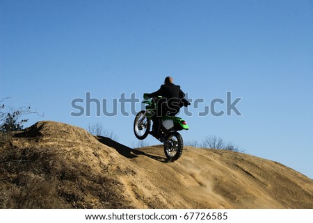Business man in suit on dirt bike.