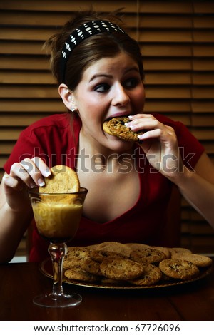 Young lady having a late night binge of cookies and milk.