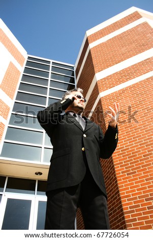 Attractive 40 year old business man in suit and sunglasses on phone outside.