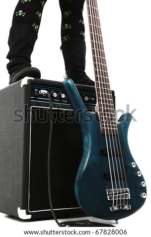 Amp and 5 string bass guitar over white with female boots legs standing on amp.