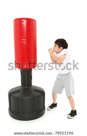 Adorable 8 year old boy practicing punches with a free standing heavy bag over white.