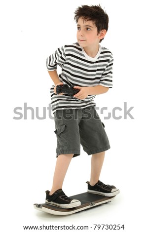 Attractive young boy on video game skateboard with joystick controller playing over white background.
