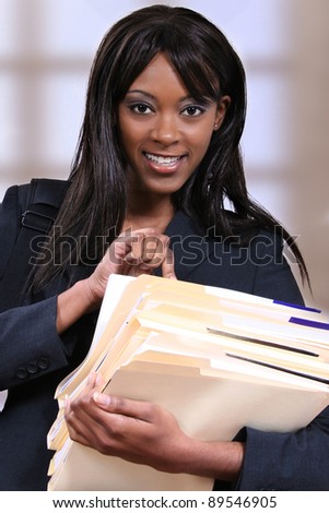 Attractive young black woman holding file folders at school or office.