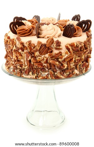 Decorated Pecan Caramel Chocolate Cake on Glass Display Platter over White Background