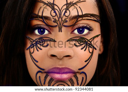 Close Up Beautiful Black Woman with Plastic Henna Art on Face and purple contact lenses.
