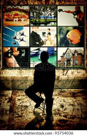 Silhouette of man sitting in front of video wall watching multimedia screens.