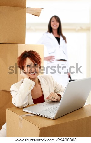 Attractive thirty year old business woman with boxes, laptop, co-worker moving into new office building.