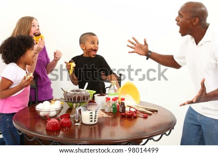 Angry dad finds kids making mess with cupcakes in the kitchen.  Interacial family over white.